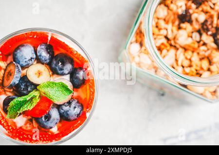 Colazione gourmet: Parfait di fragole, mirtilli e muesli con yogurt delicato, mascarpone e panna montata su sfondo grigio. SEL Foto Stock
