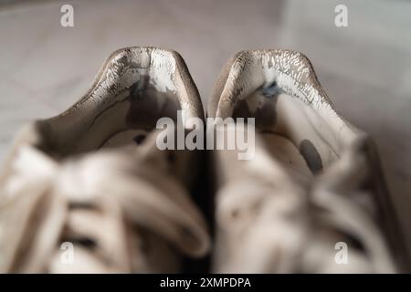 Primo piano di sneakers ben usate, che mettono in risalto l'usura, rappresentando la tendenza principale del sottoconsumo incentrata sulla sostenibilità e sulla consapevolezza Foto Stock