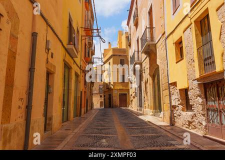 Tarragona, Spagna - 14 luglio 2024: Pittoresca strada acciottolata costeggiata da edifici colorati e balconi. Foto Stock