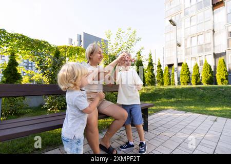 Mamma ama giocare con i due figli al parco giochi durante il pomeriggio di sole Foto Stock