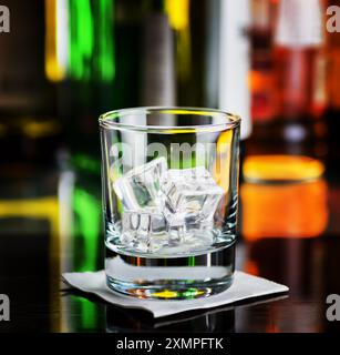 Bicchiere con cubetti di ghiaccio su una scrivania da bar Foto Stock