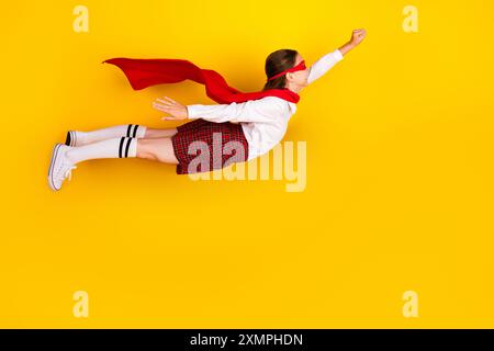 Foto a tutto corpo di una studentessa adolescente diligente supereroina volante vestita elegante e isolata su sfondo giallo Foto Stock