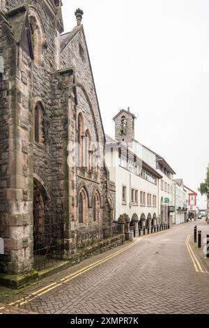 L'edificio post-modernista del quartier generale del Consiglio della contea di Gwynedd accanto alla Masonic Hall di Caernarfon (l'edificio oscuro) a Castle St Caernarfon, Galles del Nord. Foto Stock