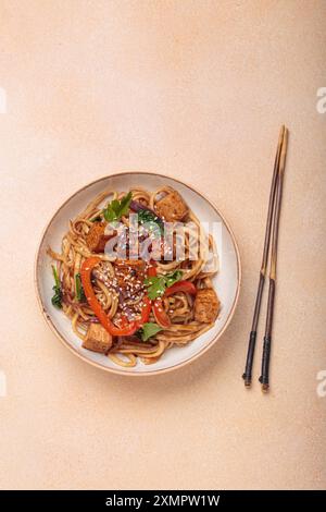 Tagliatelle Udon con tofu fritto e verdure guarnite con semi di sesamo Foto Stock