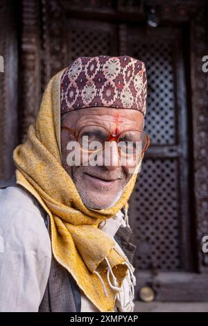 Gentiluomo nepalese che indossa il tradizionale cappello o cappellino topi di dhaka nelle strade di Kathmandu, Nepal. Foto Stock