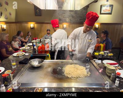 Uno chef asiatico intrattiene i clienti mentre cucinano noodles alla griglia in un ristorante teppanyaki nello Utah. Foto Stock
