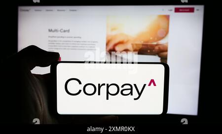 Persona che detiene un cellulare con il logo della società di pagamenti statunitense Corpay Inc. Di fronte alla pagina Web aziendale. Mettere a fuoco il display del telefono. Foto Stock