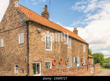 Un edificio in mattoni, ora un ristorante e pub, situato vicino a un canale chiuso sul fiume Ouse nello Yorkshire. Le cinture di salvataggio sono appese alle pareti e al cielo Foto Stock