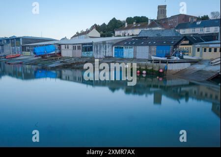 Foto a lunga esposizione di Batson Creek che crea acqua specchio con un riflesso del retro dei cantieri di Island Street con la chiesa sul retro Foto Stock