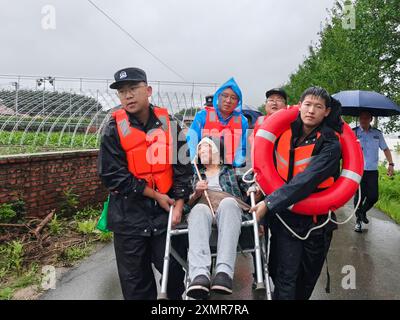 (240729) -- DANDONG, 29 luglio 2024 (Xinhua) -- gli agenti di polizia trasferiscono un residente colpito da inondazioni nella contea di Kuandian nel Dandong, provincia di Liaoning della Cina nord-orientale, 28 luglio 2024. Il tifone Gaemi ha anche portato forti piogge a Liaoning, causando l'aumento del livello dell'acqua in 17 fiumi e oltre 60 bacini idrici in tutta la provincia. Lunedì mattina, il quartier generale provinciale di controllo delle inondazioni e di soccorso contro la siccità di Liaoning ha emesso un allarme arancione per Dandong, una città di confine situata sulla riva nord-occidentale del fiume Yalu, e ha elevato il livello di risposta alle inondazioni al livello II più di 10, Foto Stock