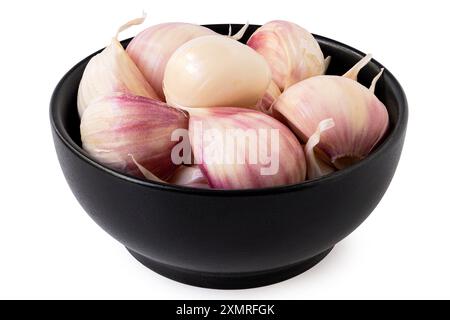 Spicchi d'aglio freschi non sbucciati in un recipiente in ceramica nera isolato su bianco. Foto Stock