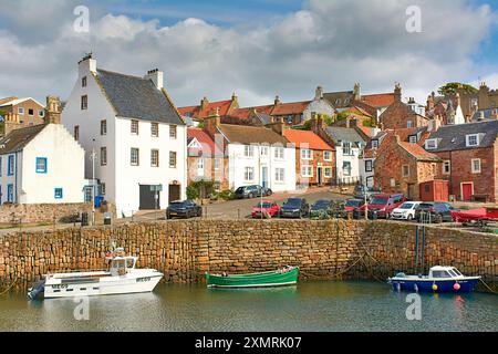 Crail Fife Scozia cielo blu e nuvole sopra le pietre delle mura del porto, le case e i pescherecci ormeggiati in estate Foto Stock