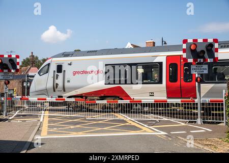 Greater Anglia Train attraversa un incrocio a Woodbridge, Suffolk, Regno Unito Foto Stock