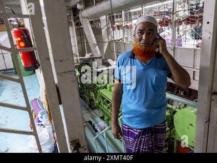 Bengalese con barba rossa che chiama al telefono nella sala macchine del traghetto, Divisione di Dacca, Dacca, Bangladesh Foto Stock