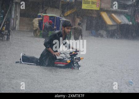 Rawalpindi, Pakistan. 29 luglio 2024. Un uomo spinge una motocicletta su una strada allagata durante una forte pioggia monsonica a Rawalpindi, Pakistan, il 29 luglio 2024. Crediti: Str/Xinhua/Alamy Live News Foto Stock