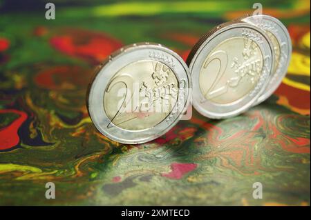 Nuove e brillanti monete da 2 euro su una superficie astratta a chiazze. Primo piano Foto Stock