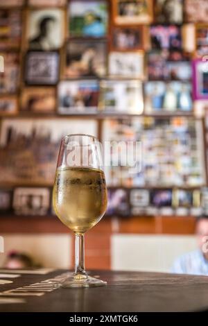 Primo piano di un rinfrescante bicchiere di vino manzanilla in una tradizionale taberna a Sanlucar de Barrameda, Spagna, con un'atmosfera calda e invitante. Foto Stock