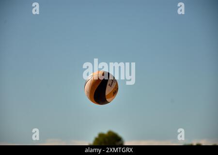 Un momento ricco di azione del torneo 3x3 di pallavolo in spiaggia di Ladeira a Baiona cattura un pallavolo che vola in aria. La scena dinamica ciao Foto Stock