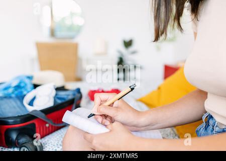 Vista ravvicinata di una giovane donna che fa una lista di controllo delle vacanze estive Foto Stock