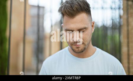 Bel giovane ispanico con una barba che contempla all'aperto in una strada urbana, trasuda un comportamento calmo. Foto Stock