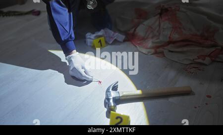 Esperto legale in guanti sulla scena del crimine con martello sanguinoso e cartellini di prova in ambienti interni Foto Stock