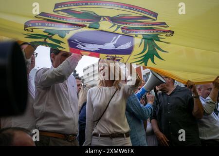 Madrid, Spagna. 29 luglio 2024. Cayetana Álvarez de Toledo (C), deputata al Congresso dei deputati di Spagna, detiene una gigantesca bandiera venezuelana durante una manifestazione alla Puerta del Sol di Madrid. I venezuelani che vivono in Spagna si sono riuniti questo pomeriggio alla Puerta del Sol di Madrid in occasione della celebrazione delle elezioni presidenziali venezuelane e a sostegno del candidato Edmundo González e del leader dell'opposizione, María Corina Machado. Hanno chiesto un riconteggio dei voti con garanzie e un processo pulito. Credito: SOPA Images Limited/Alamy Live News Foto Stock