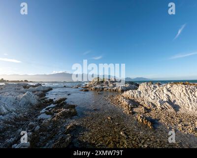 Golden Sunset Serenity: Paesaggio costiero di Kaikoura con vista sulla scogliera del mare e delle montagne, abbracciando la bellezza del sud della nuova Zelanda Foto Stock