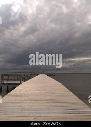 Lungo molo in legno piano che si estende fino a Barnegat Bay, New Jersey, USA. Nuvole scure coprono la baia prima di una tempesta, Foto Stock