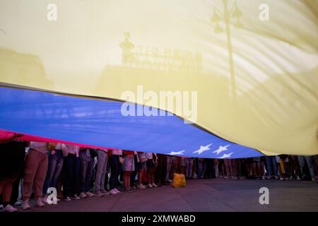 Madrid, Spagna. 29 luglio 2024. I manifestanti hanno una bandiera venezuelana gigante, durante una manifestazione a Puerta del Sol nel centro di Madrid. La comunità venezuelana residente a Madrid ha chiesto una protesta contro i risultati elettorali in Venezuela. Credito: SOPA Images Limited/Alamy Live News Foto Stock