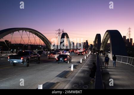 La notte di apertura sul viadotto della Sixth Street pieno di traffico tra gli archi del ponte sul fiume Los Angeles Foto Stock