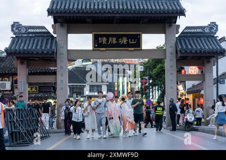 suzhou, Cina - 10 giugno 2024: Un tradizionale arco cinese a Suzhou, Cina, con persone che camminano sotto. Foto Stock