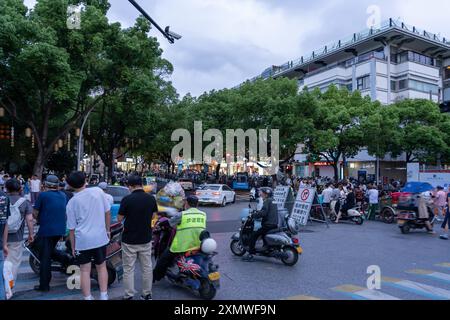 suzhou, Cina - 10 giugno 2024: Una strada trafficata a Suzhou, in Cina, piena di persone e moto. Foto Stock