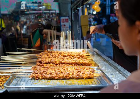 suzhou, Cina - 10 giugno 2024: Un venditore di Street food a Suzhou, Cina, vende spiedini alla griglia. Foto Stock