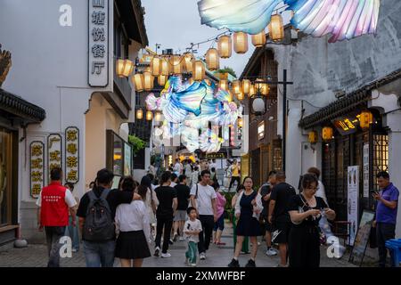 suzhou, Cina - 10 giugno 2024: Una vivace strada a Suzhou, in Cina, illuminata da lanterne tradizionali e decorazioni colorate. Foto Stock