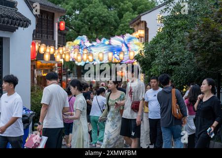 suzhou, Cina - 10 giugno 2024: Folle di persone passeggiano per le strade di Suzhou, in Cina, illuminate da lanterne colorate. Foto Stock