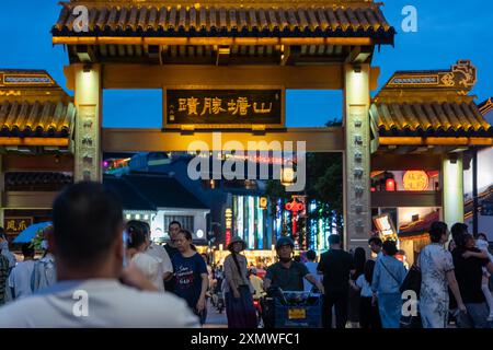 suzhou, Cina - 10 giugno 2024: Una tradizionale arcata a Suzhou, Cina, illuminata di notte, con persone che camminano. Foto Stock