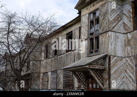 Finestre a bordo. Una vecchia casa in legno abbandonata con finestre a bordo e un tetto in rovina Foto Stock