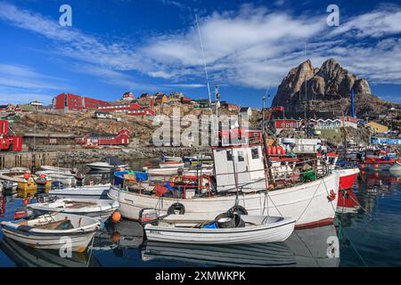 Porto con barche di fronte a un villaggio con montagne, soleggiate, pittoresche, Heart Mountain, Uummannaq, Groenlandia Foto Stock