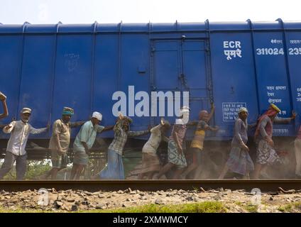 Lavoratori del Bangladesh che spingono un treno blu in linea, divisione Khulna, Abhaynagar, Bangladesh Foto Stock