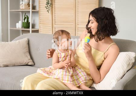 La mamma dà a casa la bibita del bambino con il cibo sul divano Foto Stock