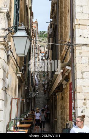 Dubrovnik, Croazia - 5 ottobre 2019: Uno stretto vicolo pieno di vita tra antichi edifici in pietra. Foto Stock