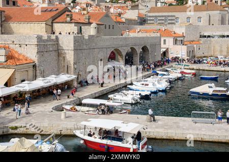 Dubrovnik, Croazia - 5 ottobre 2019: I turisti esplorano le storiche mura della città e il vivace porto pieno di barche. Foto Stock