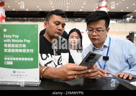 Nanjing/Guangzhou. 30 luglio 2024. Un passeggero indiano (L) chiede informazioni su WeChat Pay, una delle principali piattaforme di pagamento mobile della Cina, al Terminal 2 dell'aeroporto internazionale Guangzhou Baiyun di Guangzhou, nella provincia del Guangdong della Cina meridionale, 3 aprile 2024. Crediti: Deng Hua/Xinhua/Alamy Live News Foto Stock