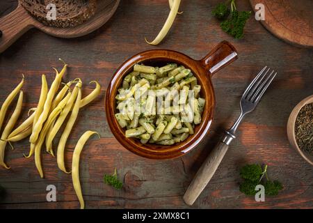 Ciotola di fagioli verdi con erbe sedute su un rustico tavolo di legno Foto Stock