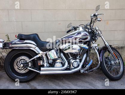 Motocicletta Harley-Davidson cromata con verniciatura personalizzata con fiamme parcheggiate contro una parete di cemento. All'annuale calne bike Meet 2024 Foto Stock