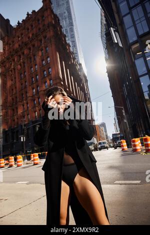 Una giovane donna balla liberamente in una strada di New York, immersa nella luce dorata di una giornata di sole. Foto Stock