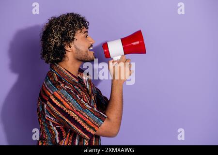 Foto del profilo laterale di un uomo divertente con una camicia stampata con barba che urla in stile megafono spazio vuoto isolato su sfondo di colore viola Foto Stock