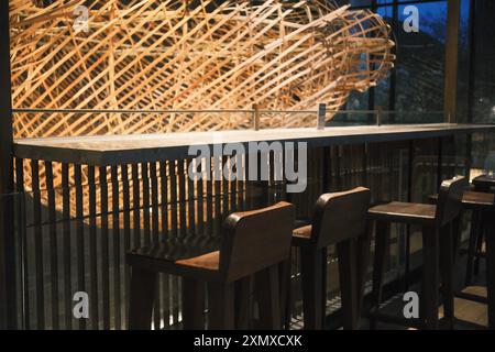 Kuta, Bali, Indonesia - 10 luglio 2024: Design degli interni caratterizzato da un bar da tavolo in granito e sgabelli in legno, completato da una grande decorazione tradizionale Foto Stock