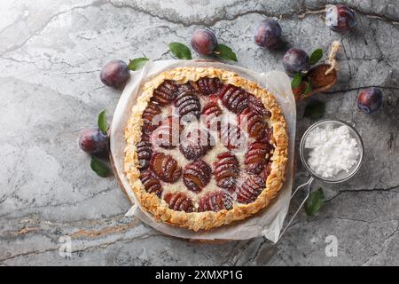 Torta di prugne appena sfornata con primo piano di mandorle su una tavola di legno sul tavolo. Vista dall'alto orizzontale Foto Stock