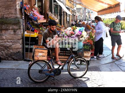 Giovane uomo che consegna fiori in bicicletta a Parma, Italia Foto Stock